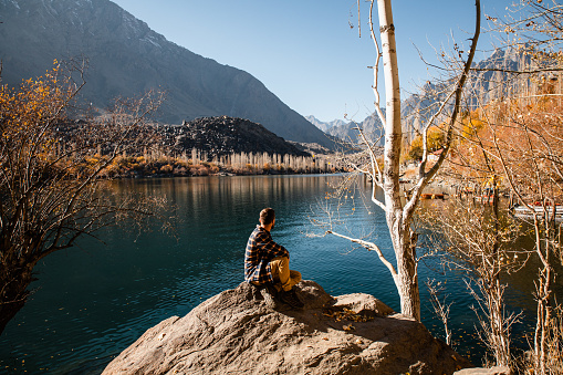 The man enjoy a scenic view of the lake in Himalayas mountains in the autumn in Pakistan