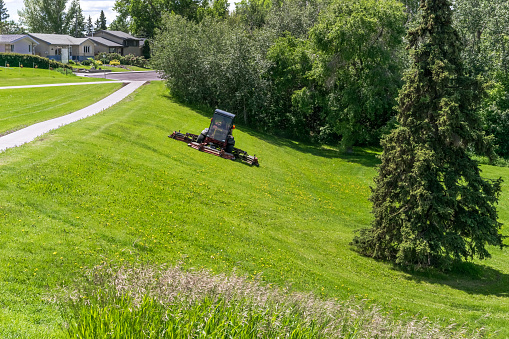 Lawn mowing on the city park slope at Mill Creek Ravine, Edmonton