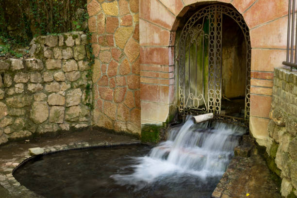 Water source with healing and hot water in Niska Banja, Serbia on spring day. Water springs from the tunnel in the forest. Long exposition of water