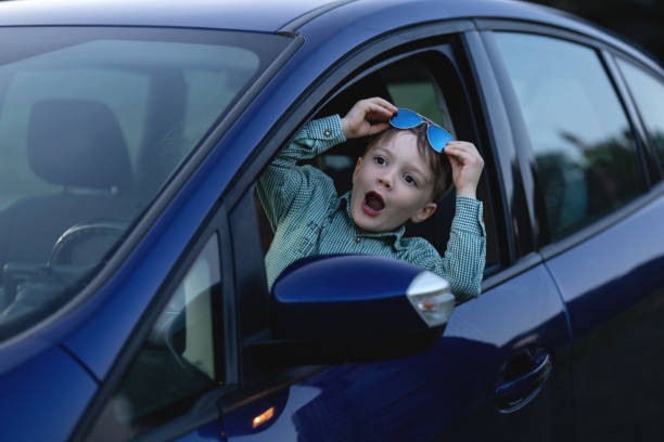 un bambino che guida l'auto di papà è felice - huckleberry finn foto e immagini stock