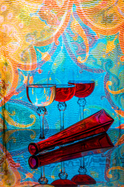 Still life with glasses and a red bottle on a colored background