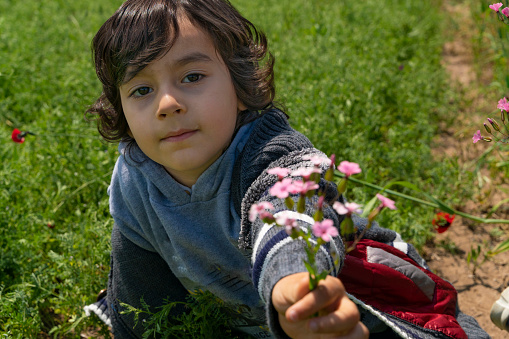 bahar çiçekleri arasında gizlenmiş erkek çocuk. kameraya bakıp gülümsüyor. gün ışığında full frame makine ile çekilmiştir.