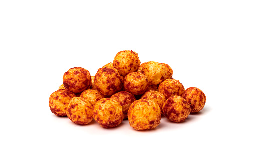 Red corn balls pile isolated. Puffs with spices, crunchy chili pepper snacks, salty corn balls side view