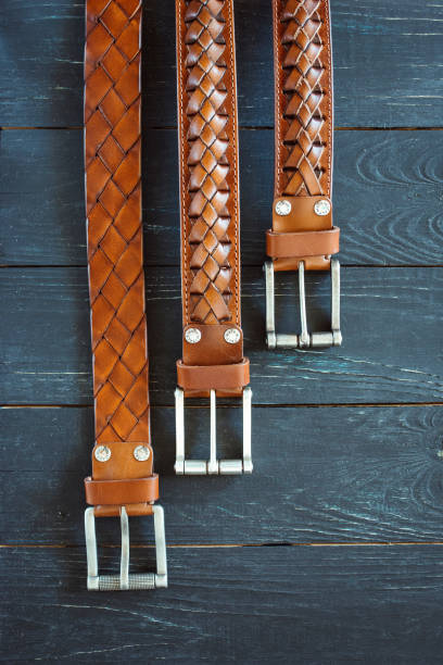 istock three leather brown belts on dark wooden background 1399066864