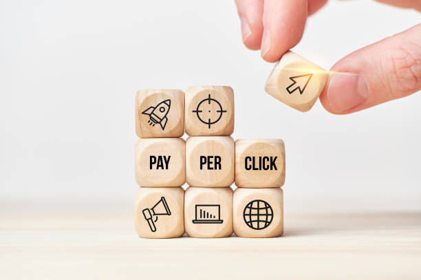Concept Pay per click or PPC. Person stacks wooden cubes from text and icons. stock photo