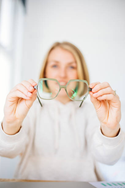 femme tenant à la main des lunettes - optics store photos et images de collection