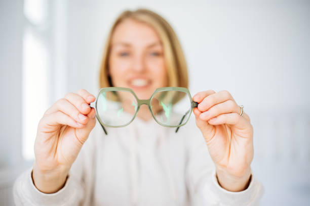 mujer con la mano sosteniendo anteojos - looking eyesight optometrist focus fotografías e imágenes de stock