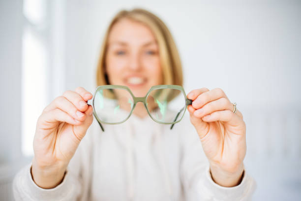 femme tenant à la main des lunettes - optics store photos et images de collection