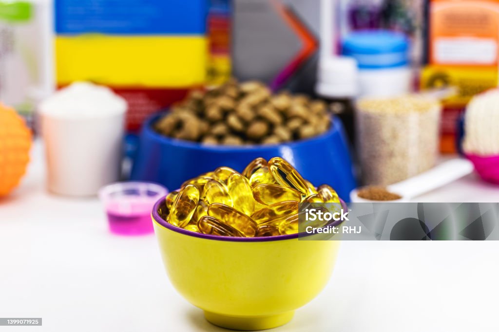 bowl with omega 3 capsules and pet food in the background, veterinary medicine. Food supplement for dogs, cats, fish or birds Dog Stock Photo