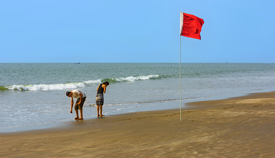 Red flag on an empty beach meaning swimming not allowed due to large waves and rough conditions at Playa de Maspalomas, popular resort in the south of the island of Gran Canaria, Canary Islands, Spain.