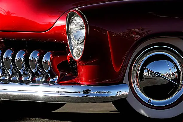 A cropped image of a fully restored classic old car with lots of shiny chrome.