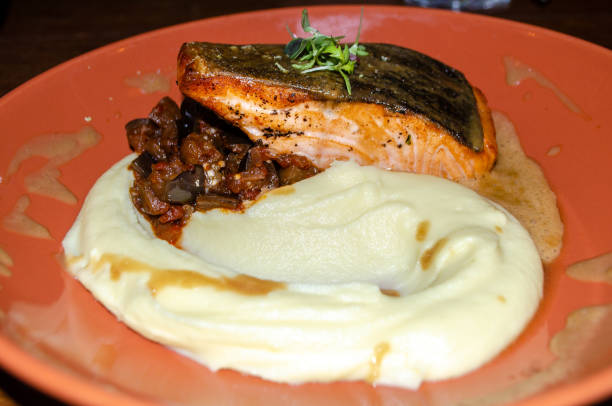 grillowany łosoś podany z puree ziemniaczanym, marynuj bakłażany ze smacznym sosem w pomarańczowym talerzu na drewnianym stole - main course salmon meal course zdjęcia i obrazy z banku zdjęć