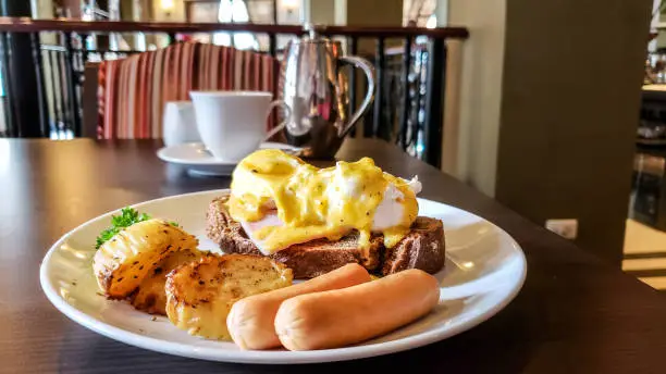 Egg Benedict with breakfast buffet choices, potato, hotdog in the hotel in Bangkok, Thailand