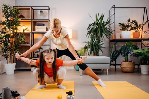 Mother and daughter doing fitness exercises in living room at home