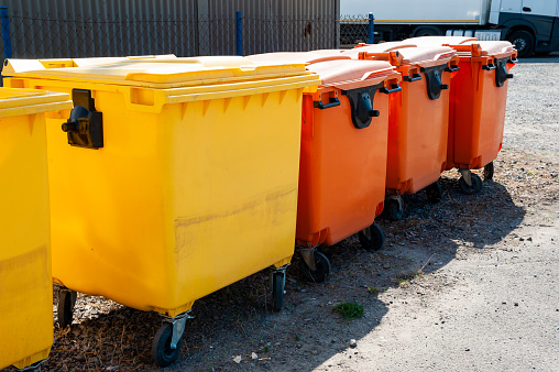 Row of orange and yellow garbage bins for sorted waste