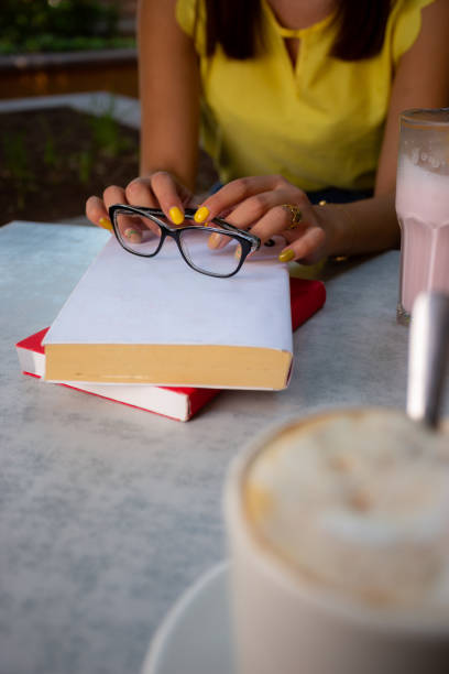 Woman reading her book, while is sitting in a table.