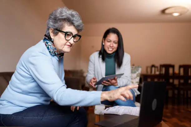 Photo of Elder woman pointing at information being showed at a laptop screen