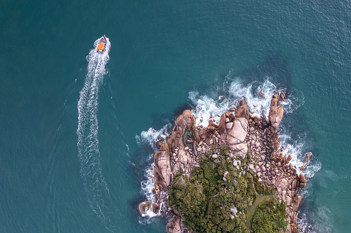 fishing boat in the sea passing by island of stones. Barra da Lagoa - Florianópolis - Santa catarina