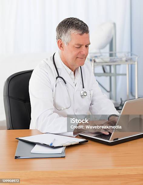 Medico Senior Lavorando Sul Suo Computer Portatile - Fotografie stock e altre immagini di Adulto - Adulto, Adulto in età matura, Clinica medica