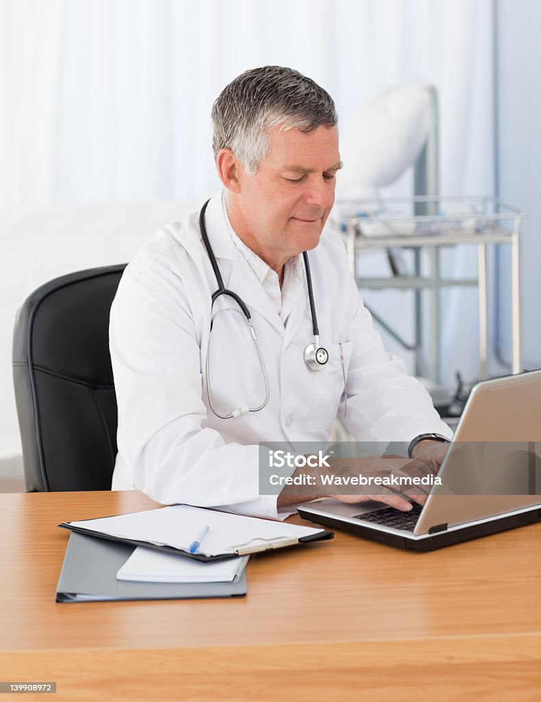 Sênior médico trabalhando em seu laptop - Foto de stock de Adulto royalty-free