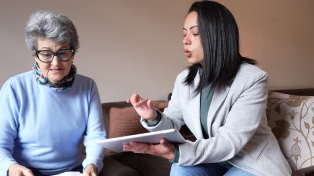Adult women explaining to an elder how to pay bills online