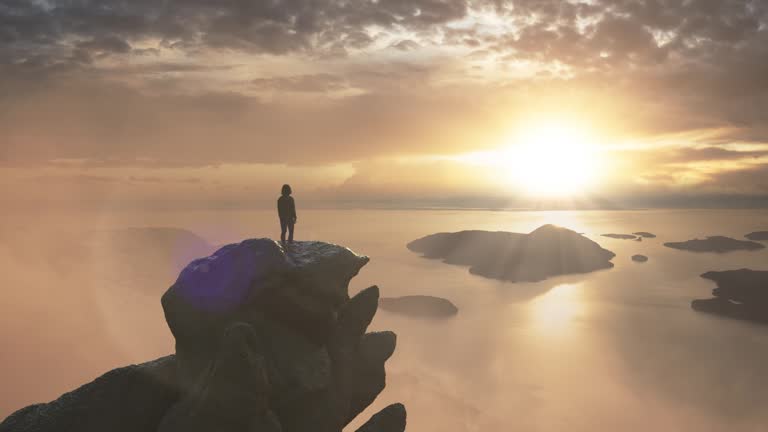 Adventurous Woman on a Rocky Mountain overlooking ocean coast