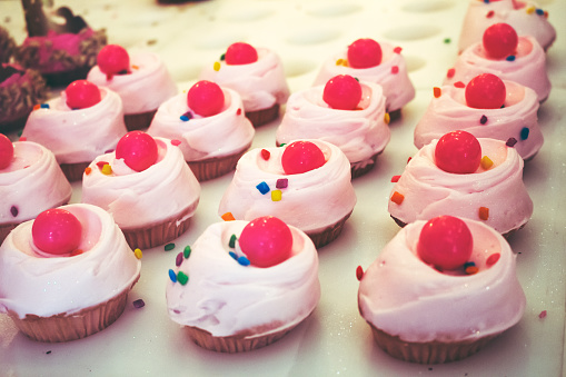 A view of several frosted cupcakes on display at a local bakery.