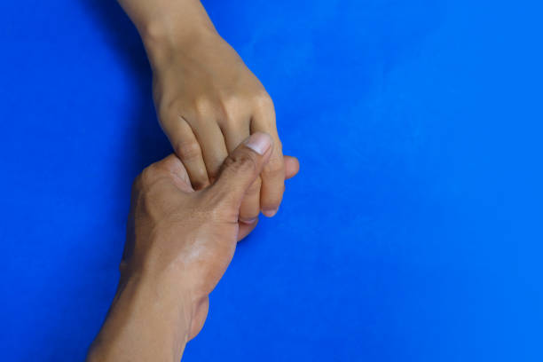 A husband holds his wife's hand on a blue background