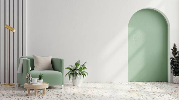 Green armchair with table on green wall and white terrazzo flooring.