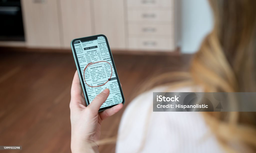 Woman looking at a real estate classified online on her phone Unrecognizable woman looking at a real estate classified online on her cell phone - For Rent Sign concepts Classified Ad Stock Photo
