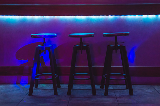 Chair in bar concept. Color neon light. Dark abstract background.