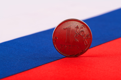 Coin in denomination of 1 Russian ruble against the background of the flag of the Russian Federation
