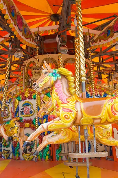 Garish painted fair ride with horses on golden poles.