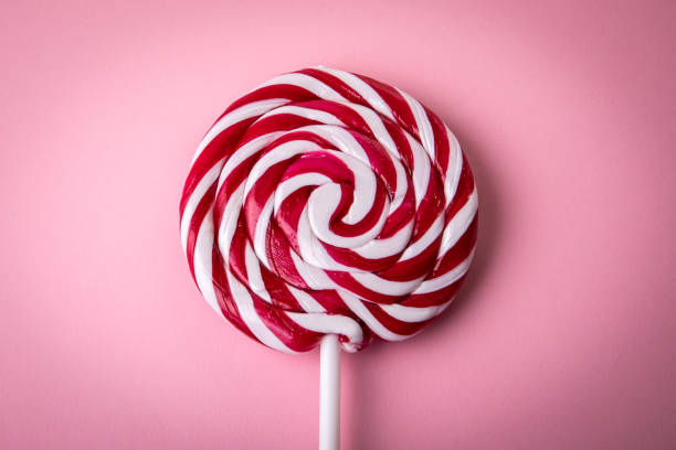 sucette rouge et blanche sur fond rose - flavored ice lollipop candy affectionate photos et images de collection