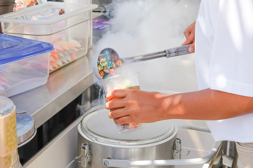 A view of an employee preparing a cup of dragon's breath cereal dessert at a food stand.