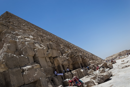 Architectural detail of the Giza pyramid complex located about 13 kilometers southwest of Cairo's city center. Far in the background, the Pyramid of Khafre or of Chephren