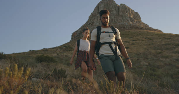 una pareja subiendo una montaña en una aventura de viaje. un joven feliz y una mujer enamorados caminando por la naturaleza - montaña de lions head fotografías e imágenes de stock