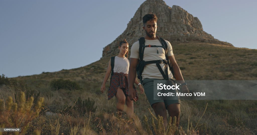 A couple hiking up a mountain on a travel adventure. A happy young man and woman in love walking through nature Hiking Stock Photo