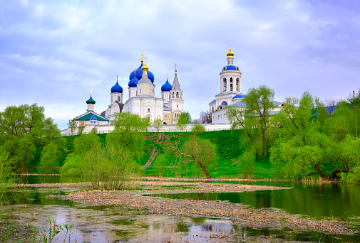 Domes of the Bogolyubov Monastery. The monastery pond in spring, the ancient Russian architecture of the temple with a bell tower in the morning. Bogolyubovo, Vladimir region, Russia, 2022