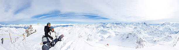 Two snowboarders on top of the mountain stock photo