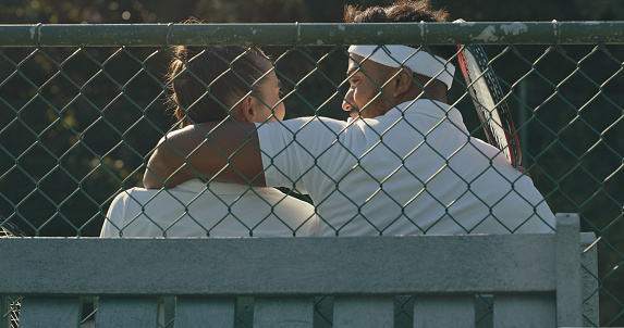 A couple relaxing, playing tennis. A young man and woman in love sharing a romantic moment after playing a game on the court