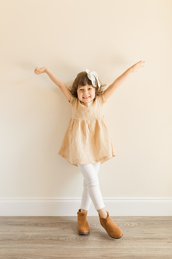 A cute young girl smiling standing and bewiledered looking up over a white background