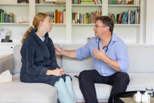 Young woman getting a home visit from a doctor stock photo