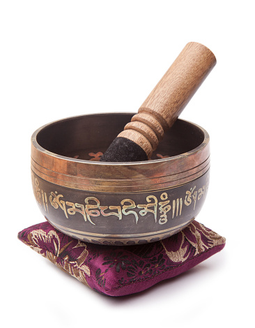 traditional Tibetan meditation and healing singing bowl on a cushion, isolate on white