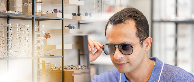 Banner style, Portrait of handsome man wearing sunglasses at optical shop, Indian male choosing sunglasses in optics store