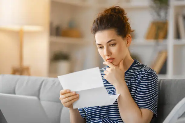 Photo of Woman, sitting on the sofa with a paper receipt