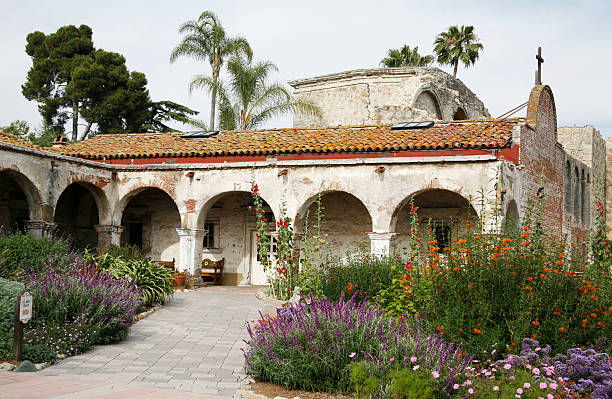A view of the Capistrano mission, include an old stone building with arches and the surrounding gardens