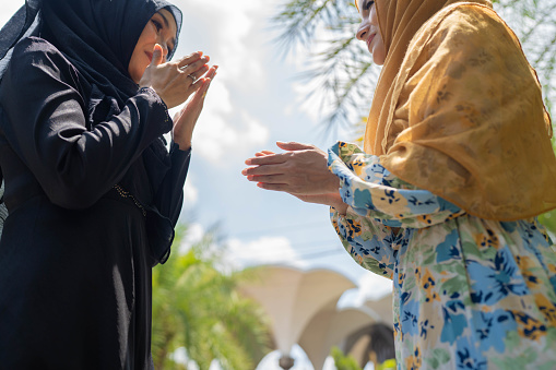Two muslim female malay ladies friend met up at Mosque in the morning and greeting to each other.