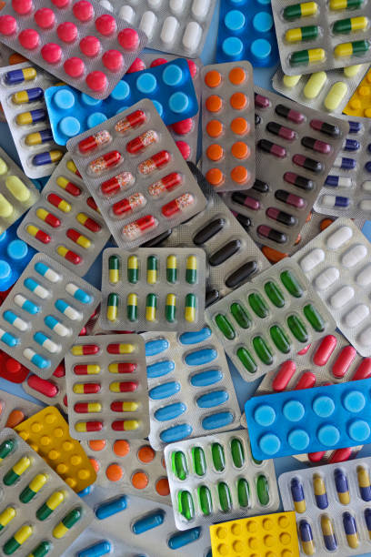 Full frame image of heap of pharmaceutical tablet blister packets, pill and gelatine capsule medicines, vibrantly coloured drugs visible through transparent plastic pockets, opaque windows, blue background, elevated view Stock photo showing close-up, elevated view of vibrantly, colourful tablet, pill and gelatine capsule medicines in blister packs. Health care and drug use concept. allergy medicine stock pictures, royalty-free photos & images