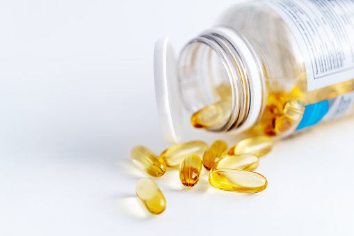 Open can with heap of transparent yellow pills, fish oil Omega 3